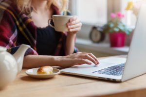 Beautiful woman relaxing at home with notebook and cup of  coffee