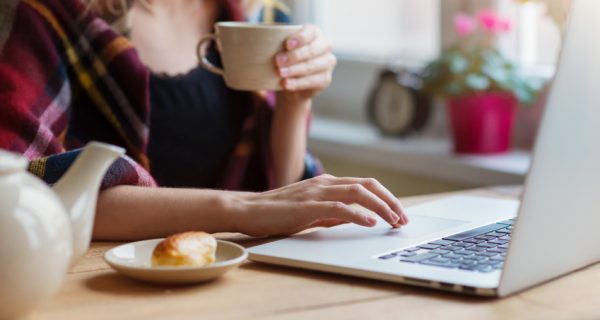 Beautiful woman relaxing at home with notebook and cup of  coffee
